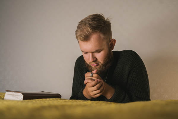 Best Devotionals for Men - man kneeling at bed praying