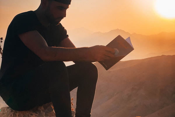 Man reading at sunset on mountain